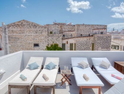 Tumbonas en la terraza del hotel Can Albertí 1740 con las casas de Mahón al fondo