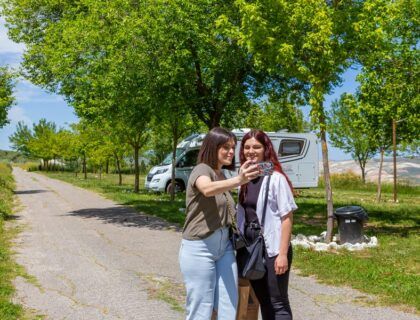 dos mujeres posan junto a una autocaravana en dona mencia